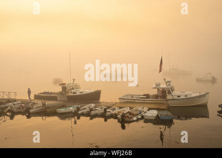 Testa Lobstermen in acqua durante una mattinata nebbiosa sunrise a cinque delle isole Harbor, Maine. Foto Stock