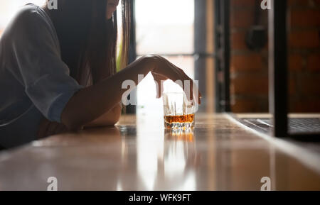 Triste donna bevitore azienda bicchiere di whiskey di bere da solo in bar Foto Stock