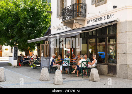 Vista sulla strada con persone sedute in un bistrot caffetteria sul marciapiede nel centro di Chamonix-Mont-Blanc in estate, alta Savoia, Francia Foto Stock