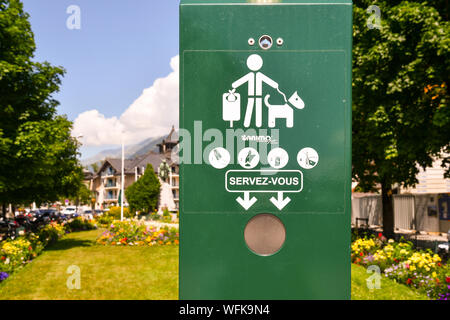 Un cane il sacchetto dei rifiuti erogatore in un parco pubblico di Chamonix-Mont-Blanc con rigogliosi bedflowers e alberi in background in estate, Haute Savoie, Francia Foto Stock