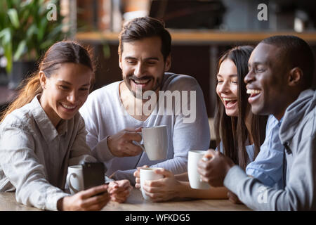 Felice diversi amici prendendo gruppo selfie sul cellulare in cafe Foto Stock