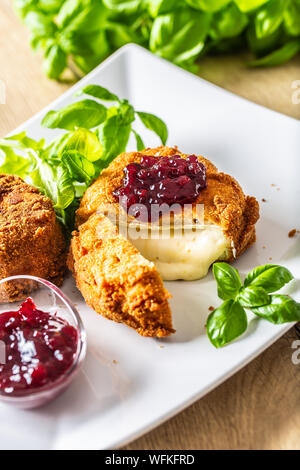 Camembert fritto o formaggio brie con marmellata di mirtilli e basilico Foto Stock