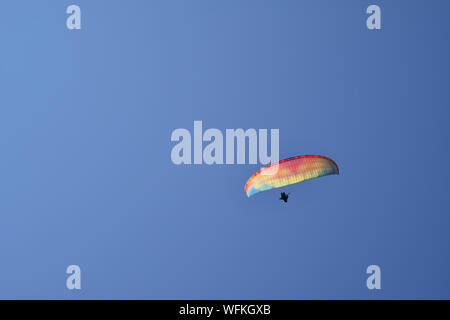 Close-up di un multicolore di parapendio in volo contro un cielo blu chiaro in estate, Chamonix-Mont-Blanc, Haute Savoie, alpi, Francia Foto Stock