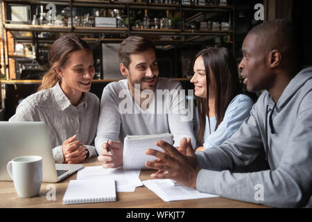 Felice multirazziale gruppo di studenti che studiano insieme sedere al tavolo del bar Foto Stock