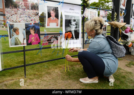 Una donna getta fiori fuori Kensington Palace a Londra, il ventiduesimo anniversario della morte di Lady Diana, principessa di Galles. Foto Stock