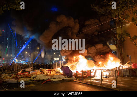 I manifestanti un incendio in prima linea nel tentativo di rallentare la polizia progressi per cancellare la strada.disordini in Hong Kong continua come migliaia di manifestanti hanno preso parte in un illegale governo anti dimostrazione. Bombe a benzina è stata generata dai dimostranti e la polizia ha sparato a cicli multipli di pallottole di gomma verso i manifestanti. Foto Stock