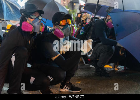 I manifestanti che indossano maschere antigas per proteggersi dalla polizia gas lacrimogeni.disordini in Hong Kong continua come migliaia di manifestanti hanno preso parte in un illegale governo anti dimostrazione. Bombe a benzina è stata generata dai dimostranti e la polizia ha sparato a cicli multipli di pallottole di gomma verso i manifestanti. Foto Stock