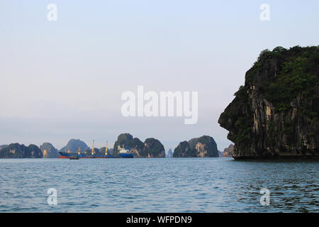 romantica e misteriosa giornata di nebbie nella baia di ha along, in vietnam. Barche in ha lunga baia con le scogliere nebbie sullo sfondo Foto Stock