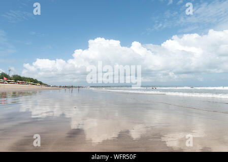 Nuvole bianche riflessa sulla sabbia bagnata sulla spiaggia di Legian Bali Indonesia su una bella giornata nella stagione secca Foto Stock