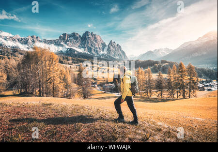Un giovane uomo con giacca gialla e zaino sta camminando il meado Foto Stock