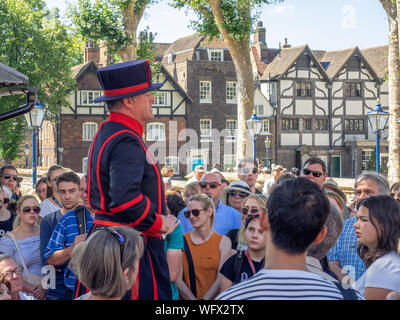 Londra, Inghilterra - 5 Agosto 2018: Un Yeomen Warder all'interno della Torre di Londra in una calda giornata estiva dando un discorso a un gruppo. Questo storico Castello Normanno Foto Stock