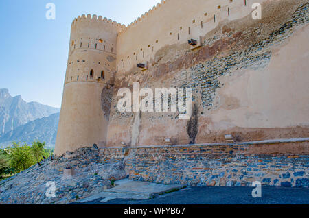 Il magnifico Fort parete con una torre di guardia vicino alle montagne e un cielo blu chiaro in background. Da Muscat Oman. Foto Stock