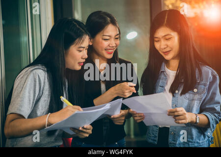 Asian più giovane donna freelance parlando con toothy volto sorridente in ufficio in casa Foto Stock