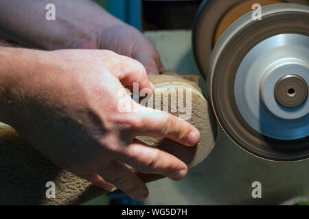 Calzolaio maschio mani la macinazione e la conformazione di una suola nella sua bottega, vicino. Foto Stock