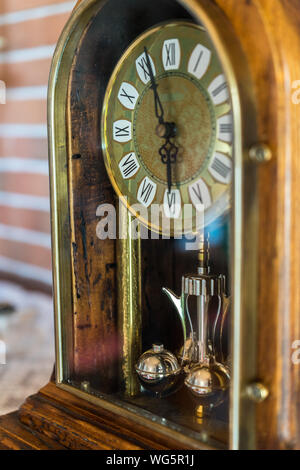 Un primo piano di un antico in legno dorato orologio con muro di mattoni in background Foto Stock