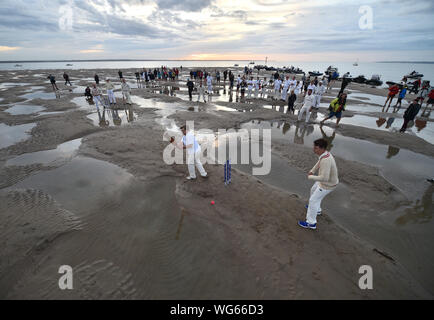 I membri della Royal Southern Yacht Club e l'isola Sailing Club di prendere parte durante l'annuale Brambles partita di cricket tra i club, che si svolge il rovo Bank sandbank nel mezzo del Solent con la bassa marea. Foto Stock