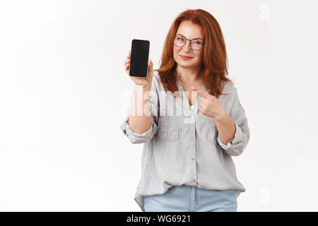 Meglio controllare di persona. Successo assicurato di mezza età redhead imprenditrice la condivisione di segreti professionali in attesa di puntamento dello smartphone schermata telefono pro Foto Stock