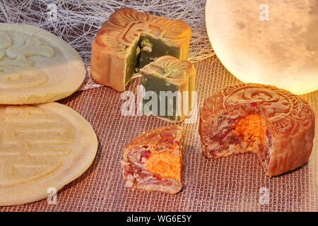 Round mooncake riempito 8 cereali e uova salate e quadrato riempito mooncake pasta di fagiolo rossa agitata nel tè verde e il trito di noci di macadamia servita con Foto Stock