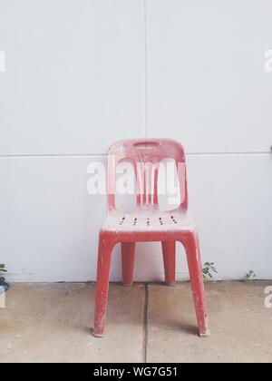 Vecchia sedia rossa sul sentiero contro la parete