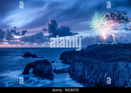 Sunset impostata a Lands End Cornwal con Enys Dodnan Arch e fuochi d'artificio sopra il faro di longship Foto Stock