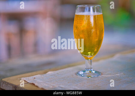 La birra. Fredda luce artigianale la birra in un bicchiere con gocce d'acqua. La birra sulla sfocatura dello sfondo. Foto Stock