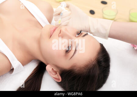 Mani di cosmetologo rendendo iniezione in viso, labbra. Giovane donna diventa bellezza iniezioni facciali in salone. Invecchiamento facciale, ringiovanimento e idratazione Foto Stock