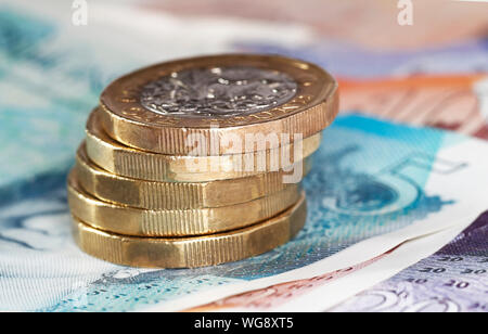 5 una libbra di monete impilate su £5 ,£10 e £20 pound note Foto Stock