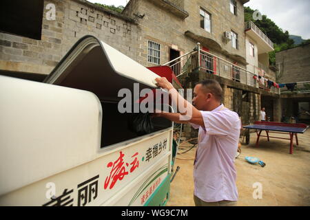 (190901) -- LINGYUN, Sett. 1, 2019 (Xinhua) -- Lao Ketuan getta trashes nel riciclare il veicolo a casa in Haokun villaggio di Lingyun County, a sud della Cina di Guangxi Zhuang Regione autonoma, il 30 agosto 2019. Lao Ketuan, 40, vive nel villaggio di montagna di Haokun, un luogo con estrema difficoltà di trasporto e di scarse risorse terrestri che gravemente ostacolato lo sviluppo locale e causato la gente qui intrappolata nella povertà. Lao famiglia sia tra quelle povere di famiglie che vivono qui. In 2016, Lao, tuttavia, aveva mai sognato che la sua famiglia potrebbe uscire dalla povertà grazie alle autorità locali di lavoro Foto Stock