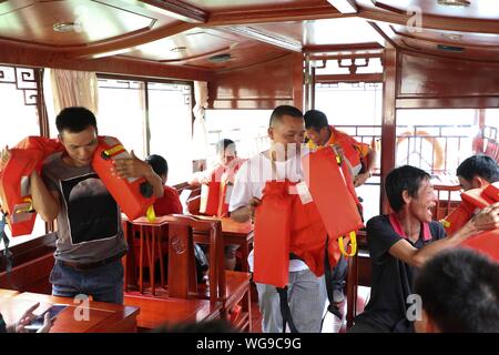 (190901) -- LINGYUN, Sett. 1, 2019 (Xinhua) -- Lao Ketuan mani giubbotti salvagente ai turisti presso il lago Haokun punto panoramico in Lingyun County, a sud della Cina di Guangxi Zhuang Regione autonoma, 31 Agosto, 2019. Lao Ketuan, 40, vive nel villaggio di montagna di Haokun, un luogo con estrema difficoltà di trasporto e di scarse risorse terrestri che gravemente ostacolato lo sviluppo locale e causato la gente qui intrappolata nella povertà. Lao famiglia sia tra quelle povere di famiglie che vivono qui. In 2016, Lao, tuttavia, aveva mai sognato che la sua famiglia potrebbe uscire dalla povertà grazie alle autorità locali di lavoro o Foto Stock