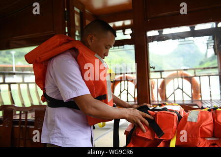 (190901) -- LINGYUN, Sett. 1, 2019 (Xinhua) -- Lao Ketuan organizza giubbotti salvagente prima di guidare la sua barca Gita al Lago Haokun punto panoramico in Lingyun County, a sud della Cina di Guangxi Zhuang Regione autonoma, il 30 agosto 2019. Lao Ketuan, 40, vive nel villaggio di montagna di Haokun, un luogo con estrema difficoltà di trasporto e di scarse risorse terrestri che gravemente ostacolato lo sviluppo locale e causato la gente qui intrappolata nella povertà. Lao famiglia sia tra quelle povere di famiglie che vivono qui. In 2016, Lao, tuttavia, aveva mai sognato che la sua famiglia potrebbe uscire dalla povertà grazie a lo Foto Stock