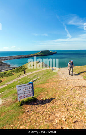 Segnale di avvertimento dando orari delle maree quando è possibile attraversare a Worms testa sulla Penisola di Gower, South Wales, Regno Unito Foto Stock