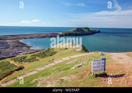 Segnale di avvertimento dando orari delle maree quando è possibile attraversare a Worms testa sulla Penisola di Gower, South Wales, Regno Unito Foto Stock