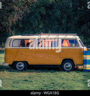 Tradizionale arancione e bianco Volkswagen camper van in campeggio Foto Stock