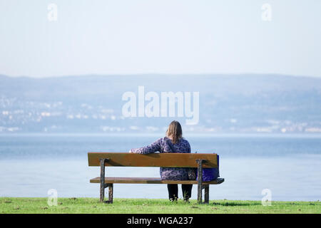 Signora sola lonely su una panchina nel parco sul mare godere di pace e tranquillità per mindfulness meditazione Foto Stock