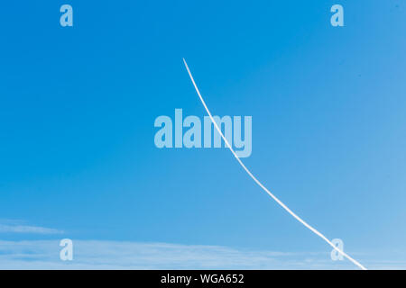 Una lunga traccia del velivolo sul cielo blu in estate Foto Stock