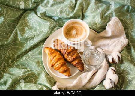 La colazione del mattino con tazza di caffè e croissant nel letto. Vista superiore Foto Stock