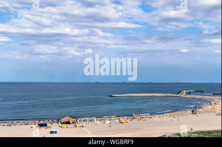 Estate spiaggia con ombrelloni e pietra wave breaker in mare Foto Stock