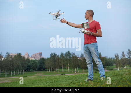 Giovane uomo comanda un quadrocopter nel parco. Foto Stock