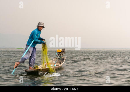 Inle, Myanmar - Marzo 2019: tradizionale birmana gamba pescatore di canottaggio a Lago Inle durante il sunrise. Foto Stock