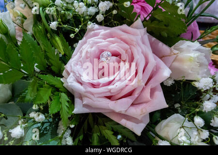 Unica rosa rosa con diamanté nel centro facente parte del bouquet nuziale Foto Stock