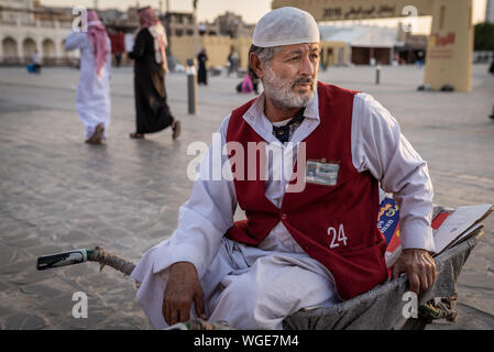 Doha, Qatar - 17 DIC 2016: un uomo porter è attesa per il suo prossimo cliente seduto su una carriola. Prese nel Souq Wakif, Doha Foto Stock