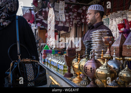 Doha, Qatar - 17 DIC 2016: un uomo street vendor è la vendita di una bottiglia di profumo per una donna che indossa un foulard islamico. Prese nel Souq Wakif, Doha Foto Stock