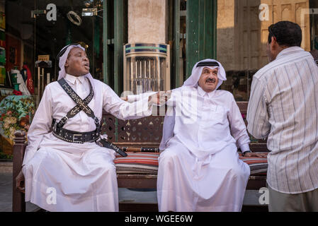 Doha, Qatar - 3 DIC 2016: due uomini dal Qatar stanno discutendo su un banco di fronte f un uomo indiano. Prese nel Souq Wakif, Doha Foto Stock