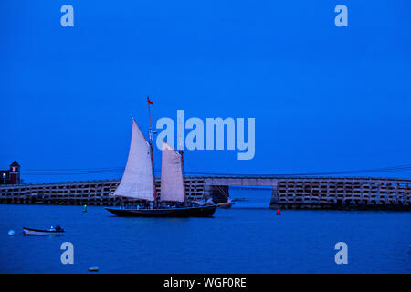 Una barca a vela Windjammer passa il Bailey Island Bridge, il granito solo cribstone ponte del mondo, a Orrs Isola, Maine. Il 1.150 piedi ponte attraversa dell intestino ed è stato realizzato con lastre di granito come cribstones senza malta o cemento. Circa 10.000 tonnellate di granito sono stati utilizzati nel progetto. Foto Stock