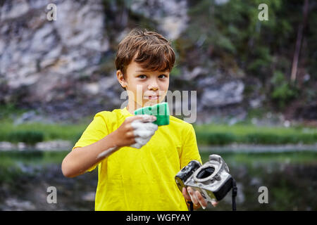 Un ragazzino fa una pulizia ad umido del sensore di immagine CMOS sul suo padre fotocamera digitale. Un naughty salviette bambino una reflex sensore di una fotocamera digitale utilizzando un Foto Stock