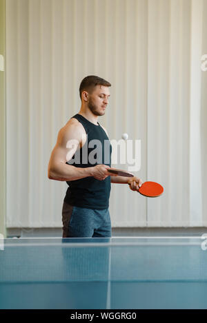 Uomo con due racchette stoffe soffia in ping pong Foto Stock