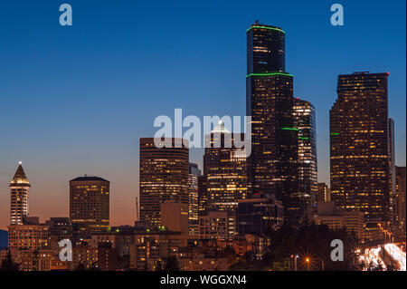 Immagine retrò dello skyline di Seattle al tramonto, con luci della città e traffico automobilistico sulla i-5 Foto Stock