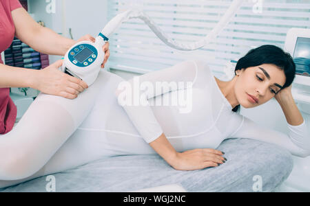 Donna getting anti cellulite con massaggio con speciali attrezzature di bellezza .Rimuovere il grasso in eccesso sui fianchi. Ottenere un perfetto corpo sottile dopo massaggio GPL Foto Stock