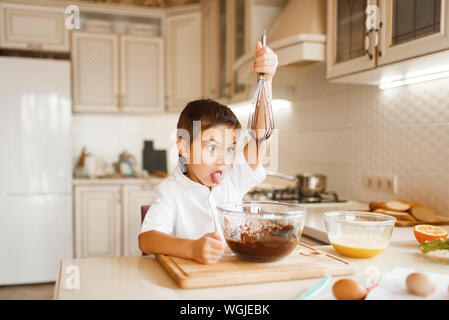 Bambino la miscelazione di cioccolato fuso in una ciotola Foto Stock