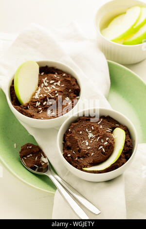 Un sano materie dessert cioccolato hummus o mousse fatta con ceci, cacao e noce di cocco o di latte di mandorla in bianco recipiente.vegane e paleo concetto alimentare Foto Stock